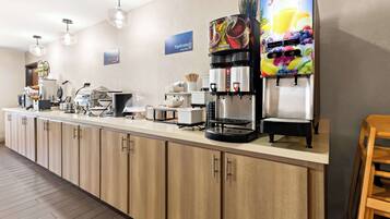 A modern breakfast bar with a juice dispenser, coffee machines, and a sign for 'Hydrate Juice'.