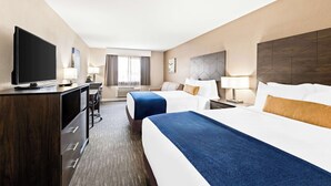 A hotel room with two beds, a desk with a TV, and a window with curtains. - Best Western Snowflake Inn (Snowflake)