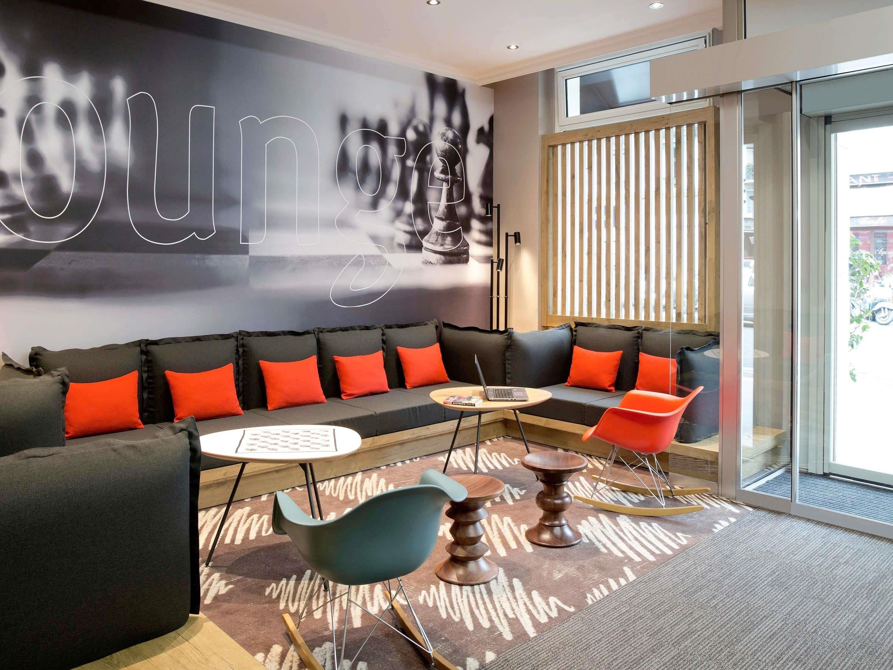 A modern lounge area with a sofa, chairs, a small table, and a laptop.