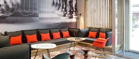 A modern lounge area with a sofa, chairs, a small table, and a laptop.
