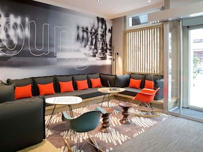 Un espacio lounge moderno con sofá, sillones, una mesita y una computadora portátil.