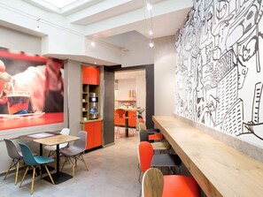 Enjoy a modern café experience with a long bar counter, comfortable seating, and a unique wall mural.