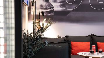 A modern interior with a sofa, a white vase with greenery, and a table with two glasses and a Coca-Cola can.