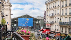 Un hôtel doté d’une grande façade en verre, une enseigne indiquant « NOUVEL HÔTEL » et une autre, à proximité, portant l’inscription « CHANGEMENT DE ».