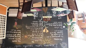 Un tableau noir avec des inscriptions et une table entourée de chaises et de verres à vin.