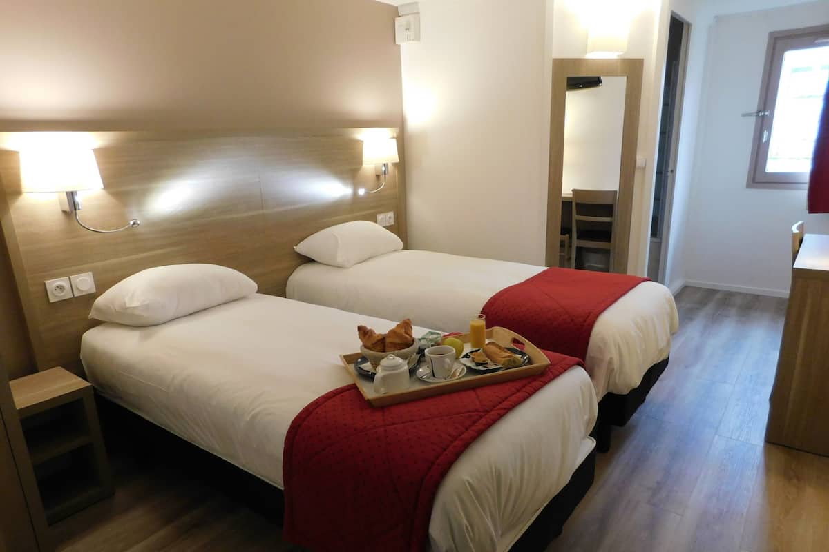 A hotel room with two beds, a tray of breakfast, and a mirror.