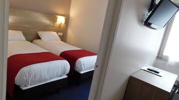 Habitación de hotel con dos camas, un escritorio y una televisión.