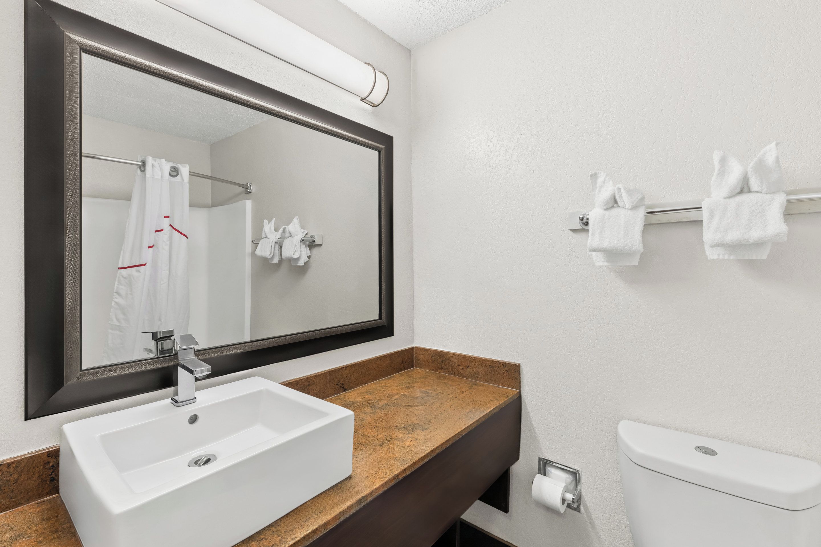 Une salle de bain avec un lavabo blanc, un miroir, un porte-serviettes et des toilettes.