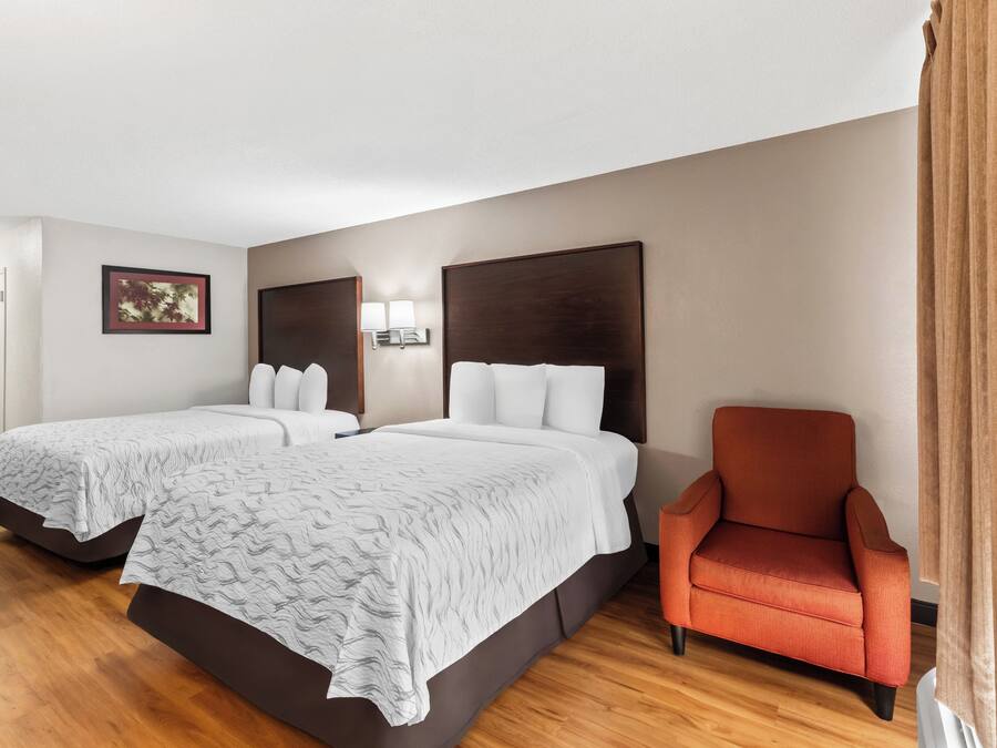 Ein Hotelzimmer mit zwei Betten, einem Sessel und einer Wandlampe.
