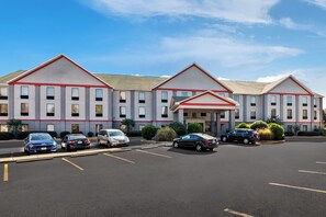 Een hotel met meerdere verdiepingen en een parkeerplaats.