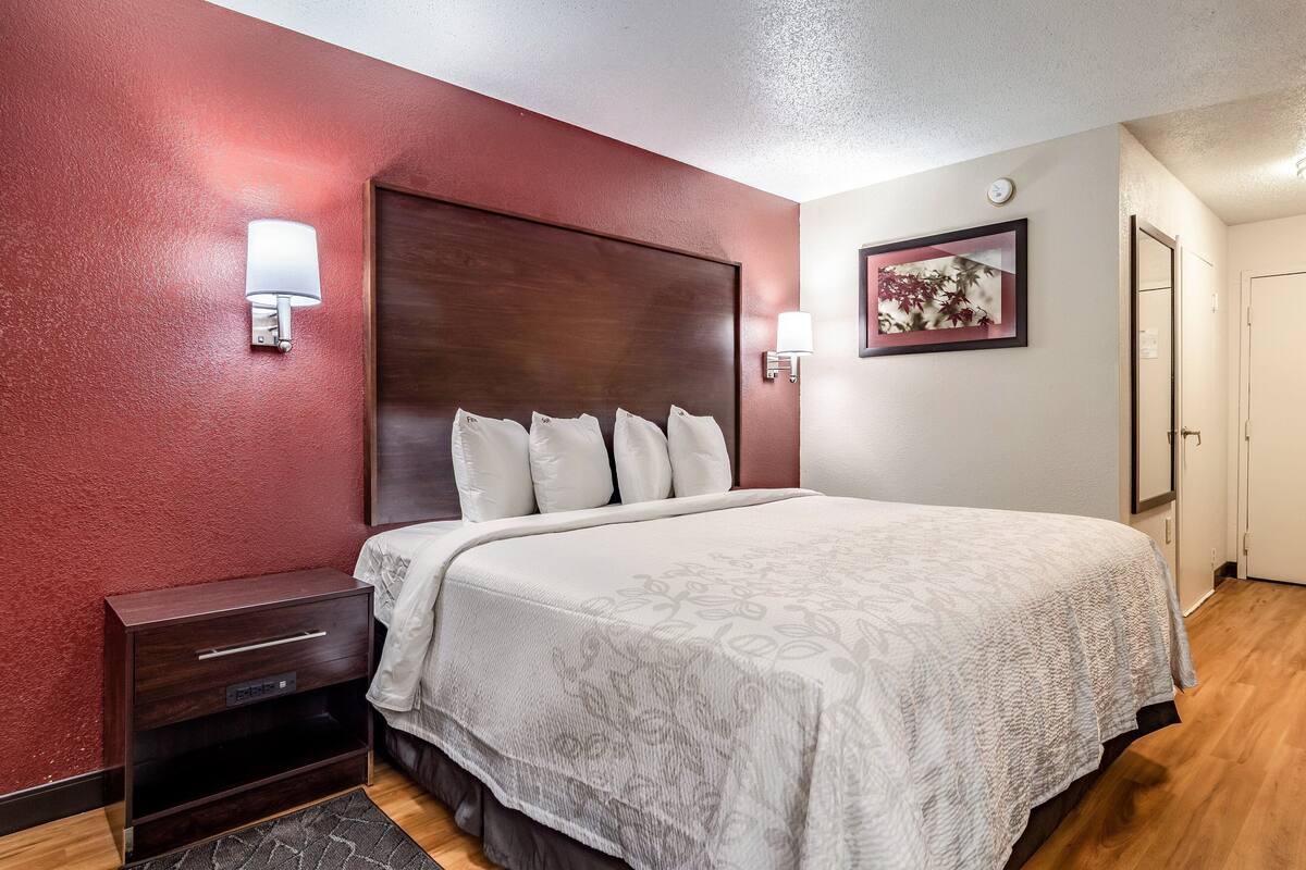 A hotel room with a large bed, two bedside tables, and a nightstand.
