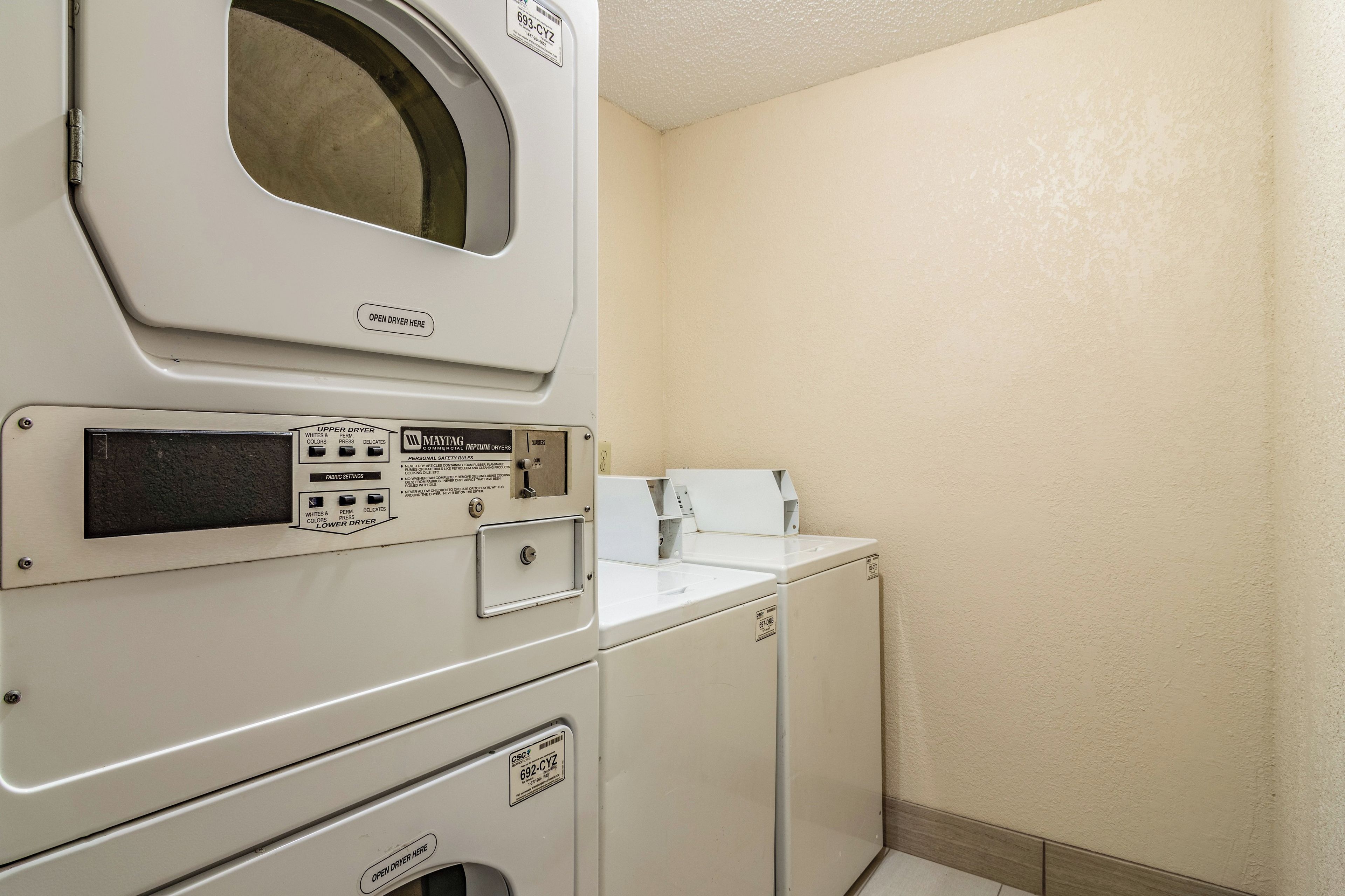 A laundry room with a front-loading washer and dryer, a control panel with various settings, and a wall-mounted dryer.