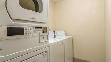 A laundry room with a front-loading washer and dryer, a control panel with various settings, and a wall-mounted dryer.