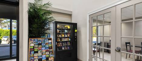 A reception area with a vending machine, a display of travel brochures, and a view of the outside.