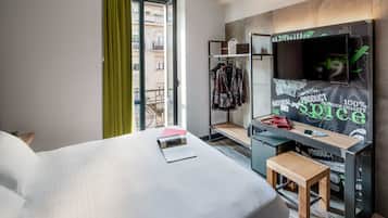 Une chambre d’hôtel avec un lit, un bureau équipé d’un ordinateur, une télévision et une vue sur l’extérieur.