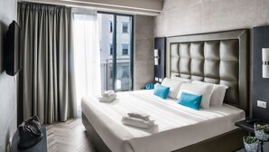 A modern hotel room with a large bed, a flat-screen TV, a desk, and a view of the city through the window. - Spice Hotel Milano (Milan)