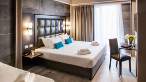 A hotel room with a large bed, a nightstand, a desk with a chair, and a vase with flowers. - Spice Hotel Milano (Milan)