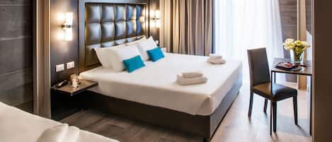 Una habitación de hotel con una cama grande, una mesita de noche, un escritorio con silla y un jarrón con flores.