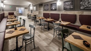 A modern restaurant with wooden tables and booths, a brick ceiling, and wall art. - Spice Hotel Milano (Milan)