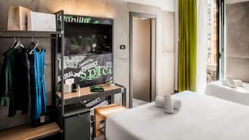 Een hotelkamer met een bed, een kledingkast, een bureau en een raam met gordijnen.