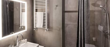 Une salle de bain moderne avec un grand miroir, un lavabo, une douche et un porte-serviettes.