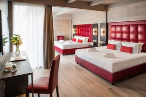 Quarto de hotel com duas camas, uma escrivaninha e uma cadeira.