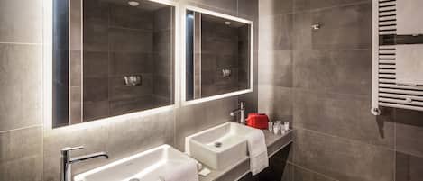 A modern bathroom with two sinks, a large mirror, and a towel rack.