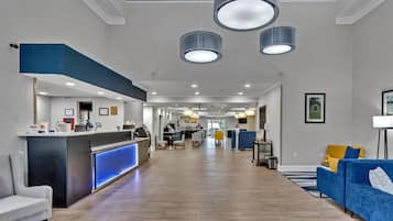 Un hall de hotel con mostrador de recepción, zona de estar y vista al comedor.