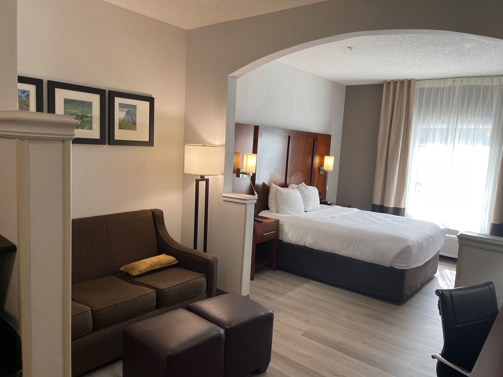 Una habitación de hotel con cama, sofá, mesita de centro, mesita de noche y lámpara.