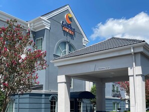 A hotel named Comfort Suites with a clear sign, a covered entrance, and a tree with pink flowers. - Comfort Suites Salisbury I-85 (Salisbury)