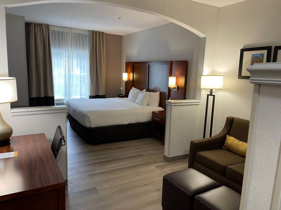 Una habitación de hotel con una cama, mesitas de noche, un escritorio, un sofá y una lámpara.