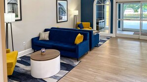 Un moderno vestíbulo con un sofá azul, una mesa de centro redonda y un sillón amarillo.