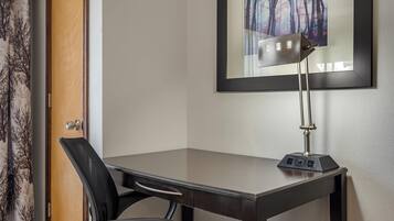 Una habitación con escritorio, silla y lámpara fijada a la pared.