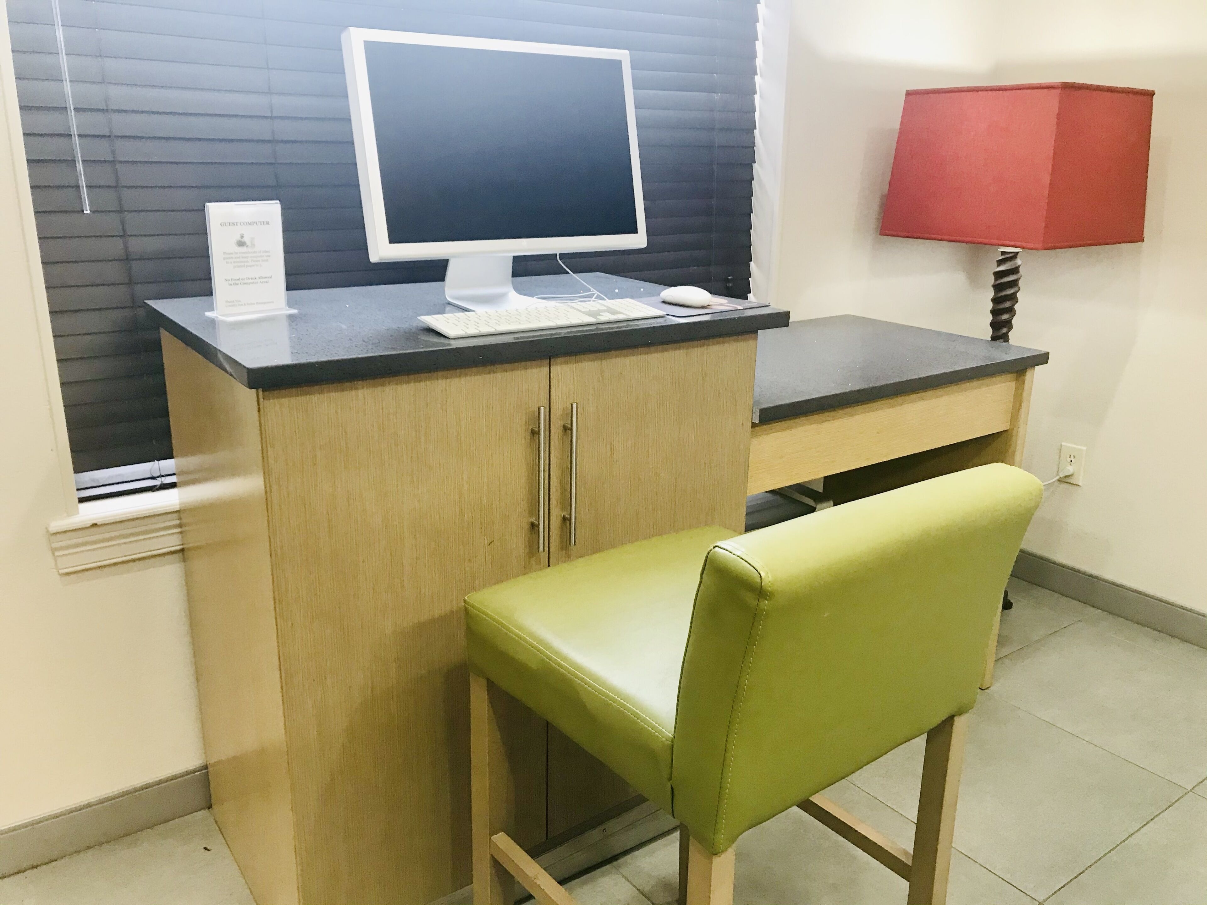 A small office space with a desk, a computer, a chair, and a lamp.