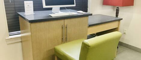 A small office space with a desk, a computer, a chair, and a lamp.