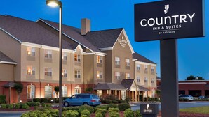 Ein Country Inn & Suites Gebäude mit Schild, Parkplatz und gepflegter Bepflanzung.