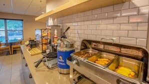 A buffet area with various food options, a coffee machine, and a beverage dispenser. - Country Inn & Suites by Radisson, Crystal Lake, IL (Crystal Lake)