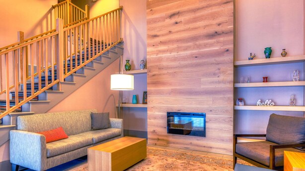 A modern living room with a staircase, a sofa, a coffee table, and a fireplace. - Country Inn & Suites by Radisson, Crystal Lake, IL (Crystal Lake)