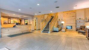 A spacious lobby with a wooden reception desk, a staircase, and a seating area with a fireplace. - Country Inn & Suites by Radisson, Crystal Lake, IL (Crystal Lake)