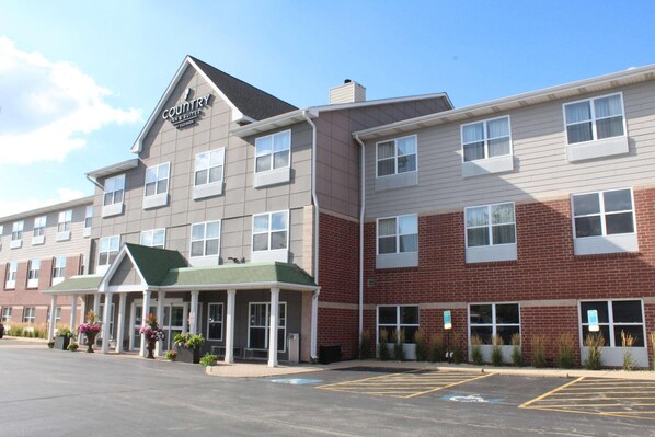 A hotel with a two-story structure, a green roof, and a parking lot with marked spaces.