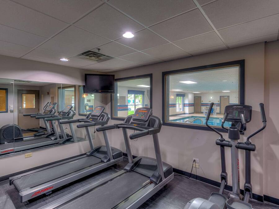 A gym with treadmills, an elliptical, and a mirrored wall.