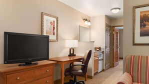 Habitación de hotel con televisión, escritorio, silla y sofá a rayas.