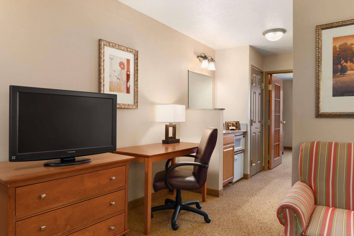 Une chambre d’hôtel équipée d’une télévision, d’un bureau, d’une chaise et d’un canapé à rayures.