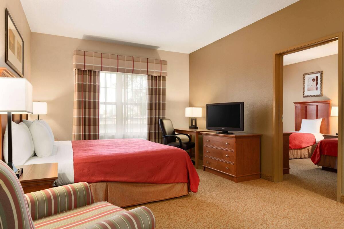 Une chambre d’hôtel avec un lit, une télévision, un bureau et une chaise.