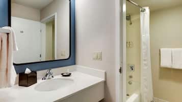 A bathroom with a white sink, a mirror, a towel rack, and a shower area.