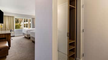 A hotel room with a bed, a desk, a chair, a wardrobe, and a window with curtains.