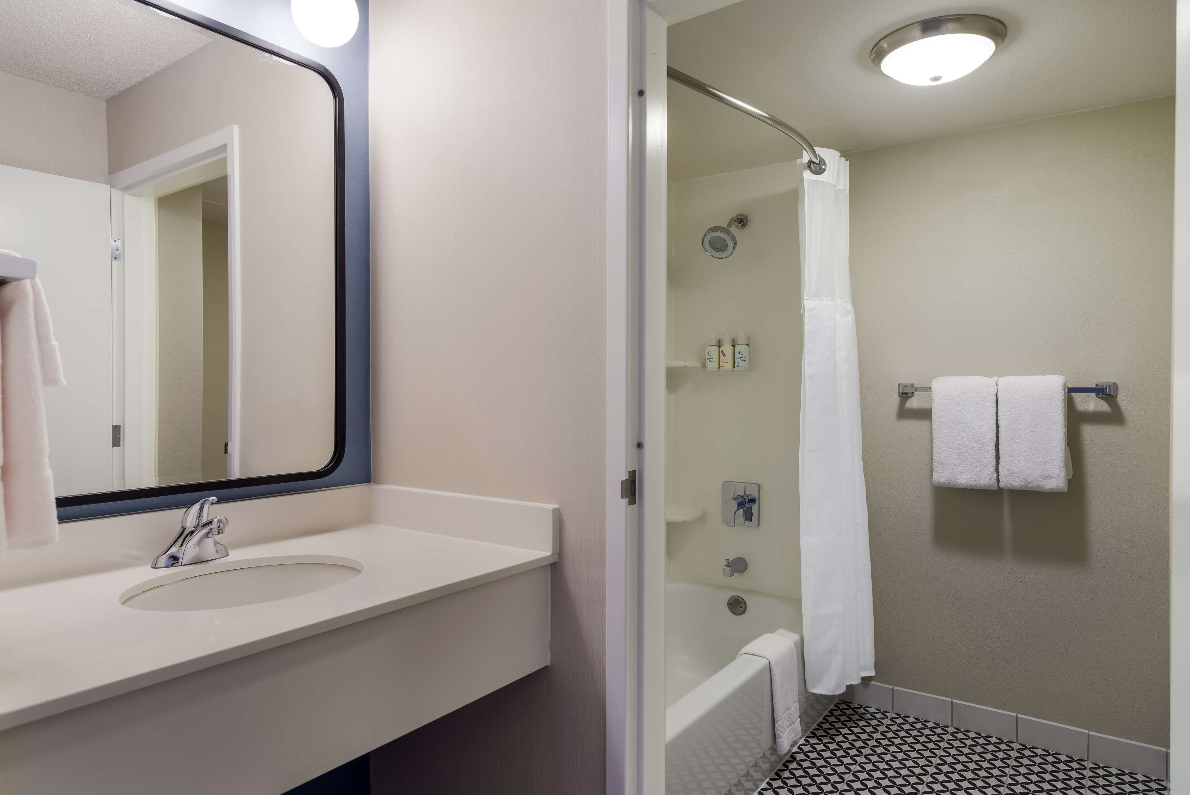 A bathroom with a white sink, a mirror, a shower with a glass door, and a bathtub.