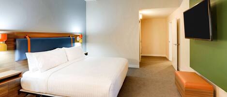 A hotel room with a bed, bedside table, and a flat-screen TV mounted on the wall.