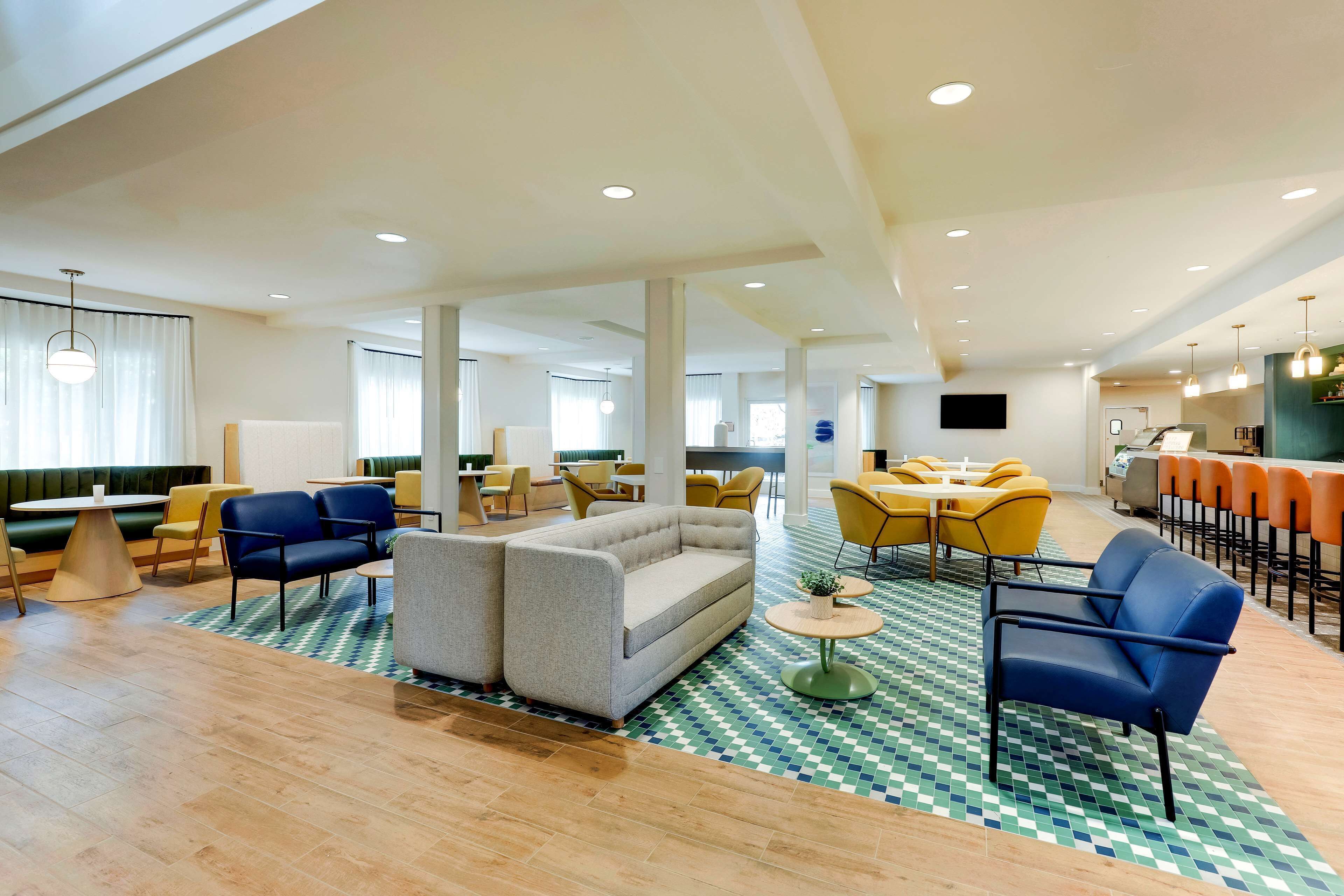 A spacious lobby with a mix of seating options including sofas and chairs, a patterned floor, and a modern ceiling design.