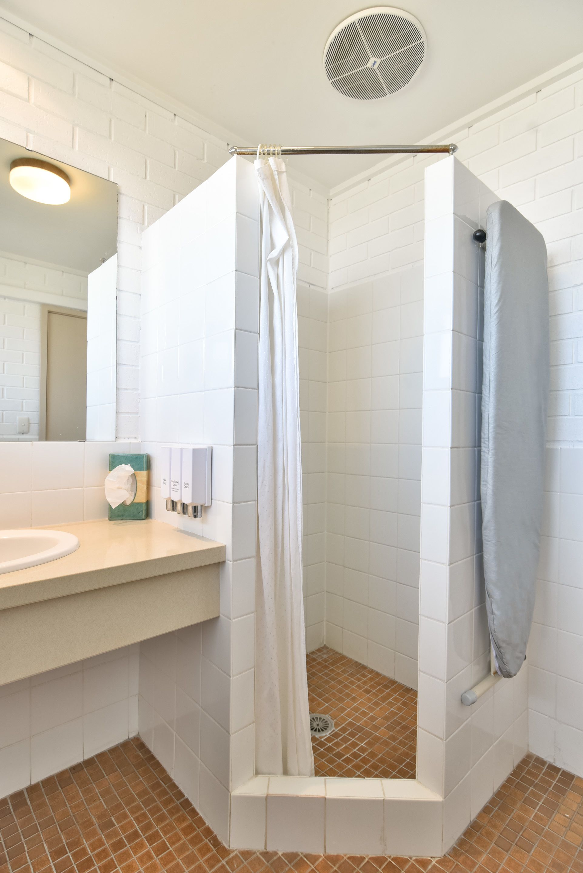Un baño con ducha blanca, lavabo y espejo.